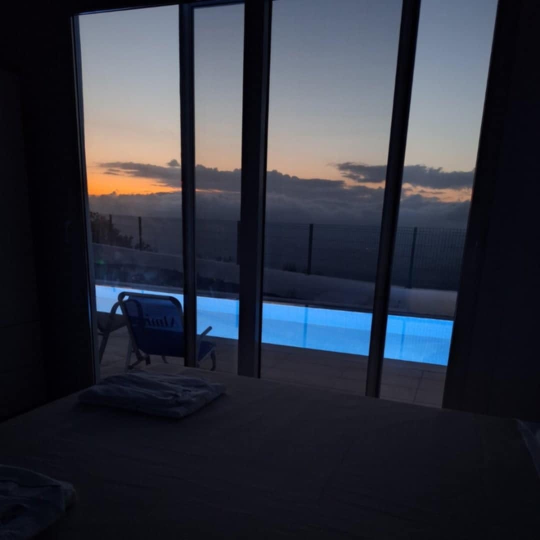 Afternoon shot from inside the room showing the bed, balcony door and the view of the pool and the mountain