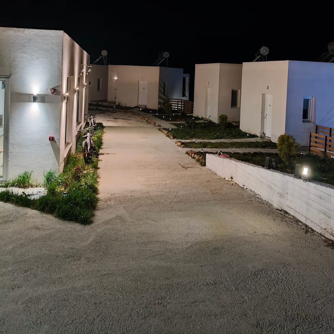 Εξωτερικός χώρος υποδοχής με τα κτίρια των δωματίων τη νύχτα